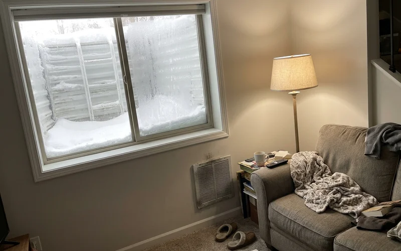 Frosted basement window well with snow outside an Iowa home
