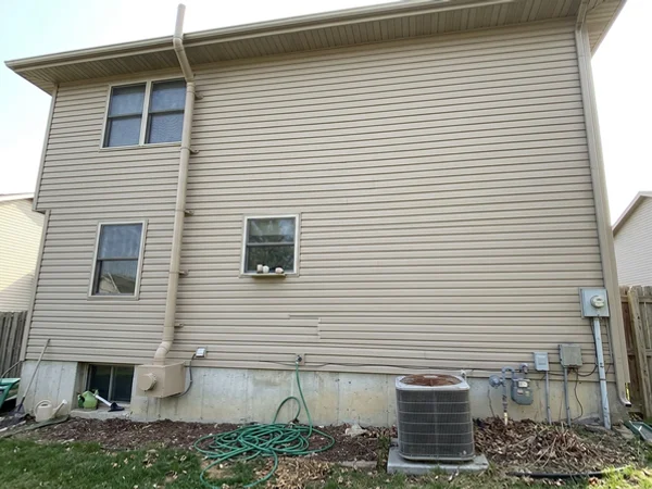 Exterior radon pipe painted to match the siding of a two-story home